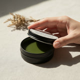 Round container of 'All Natural Calm the Cramps Salve' from Lolli and Pop Shoppe on a wooden surface.