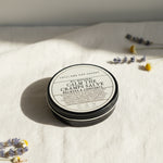 Round container of 'All Natural Calm the Cramps Salve' from Lolli and Pop Shoppe on a wooden surface.