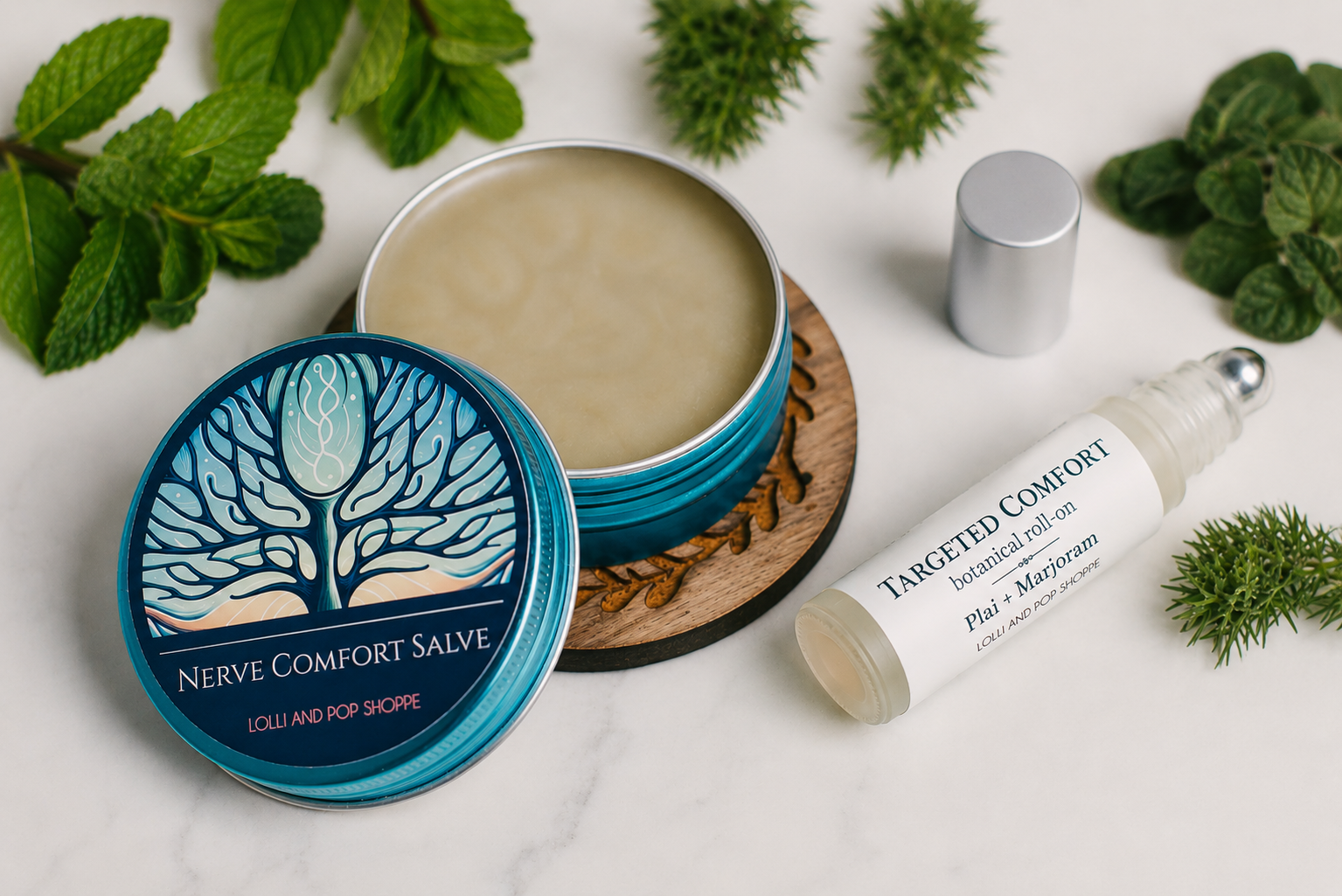 A styled flat-lay of a natural salve product showing an open teal tin of 'Nerve Comfort Salve' with its lid beside it, a silver cap, and a white rollerball bottle labeled 'Targeted Comfort Natural Roll-on' on a white marble surface surrounded by mint leaves and pine sprigs.