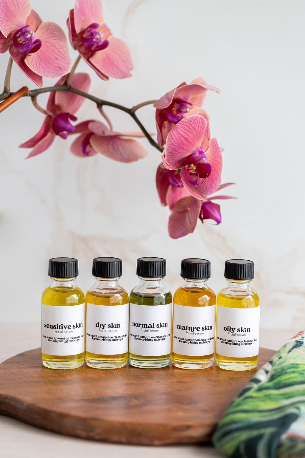 five bottles of essential oils sit on a wooden tray