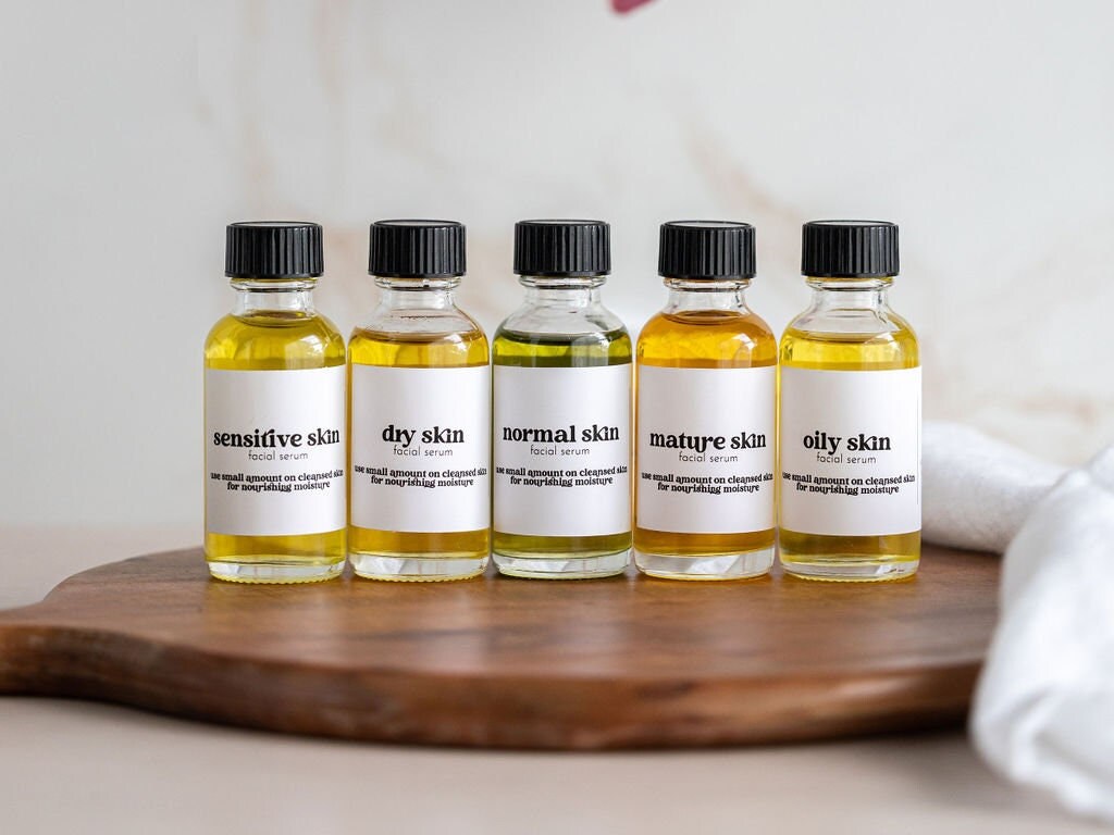 five bottles of oil sitting on top of a wooden cutting board