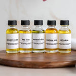 five bottles of oil sitting on top of a wooden cutting board